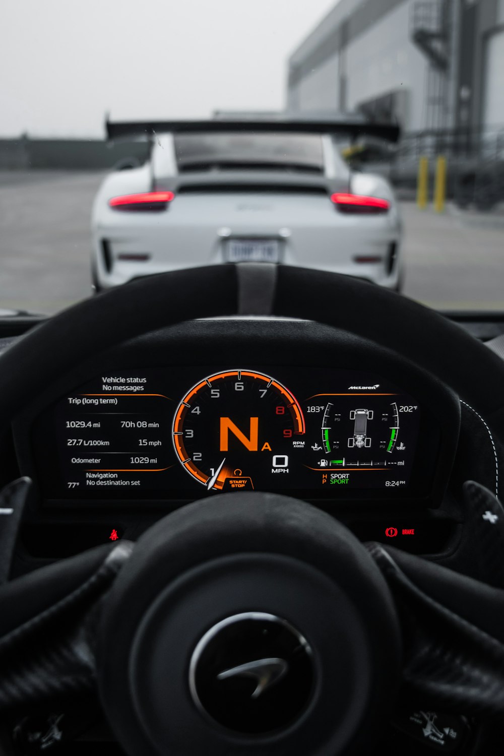 a car dashboard with a speedometer and a car in the background