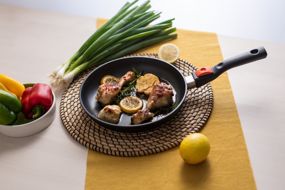 a skillet with meat and vegetables on a table