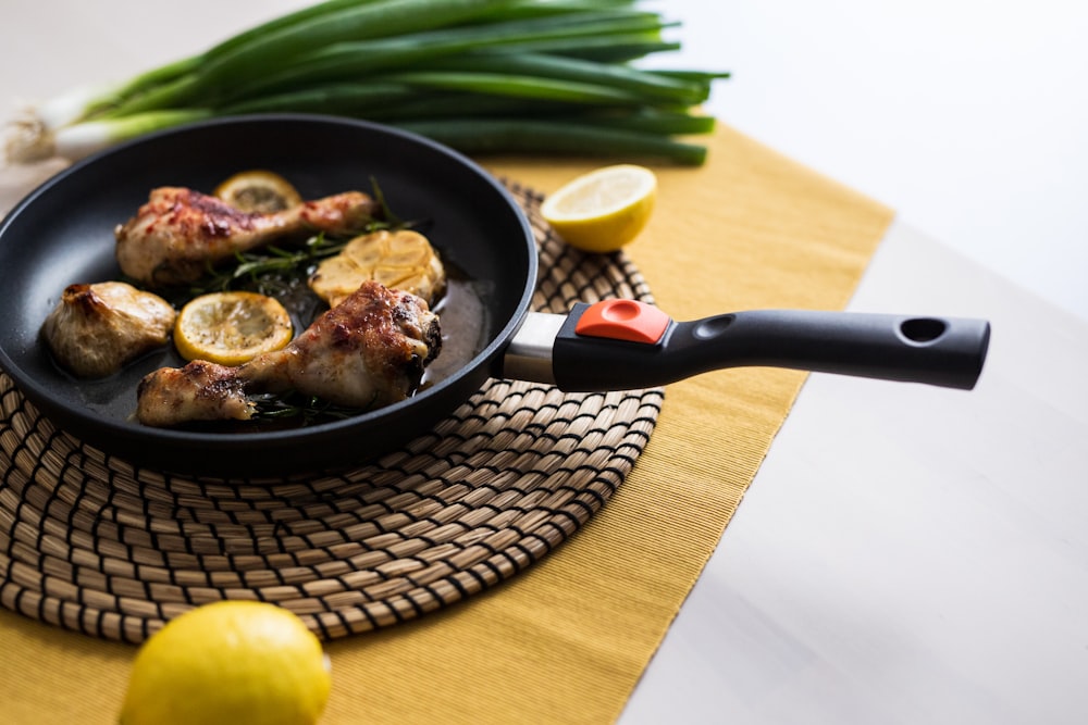 a frying pan filled with chicken and lemons