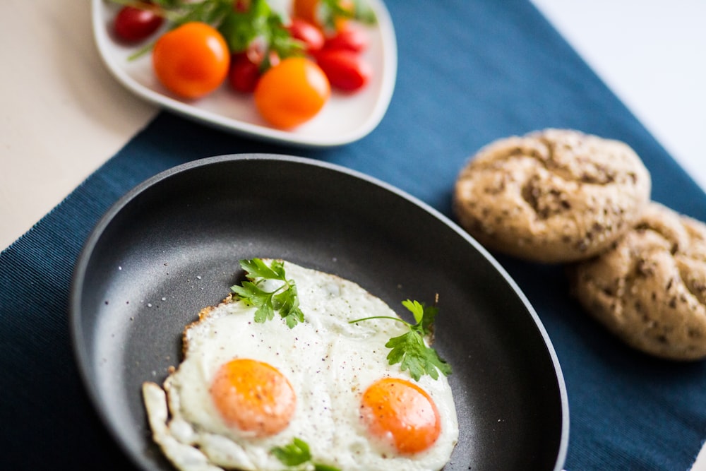 two fried eggs in a frying pan next to a plate of cookies