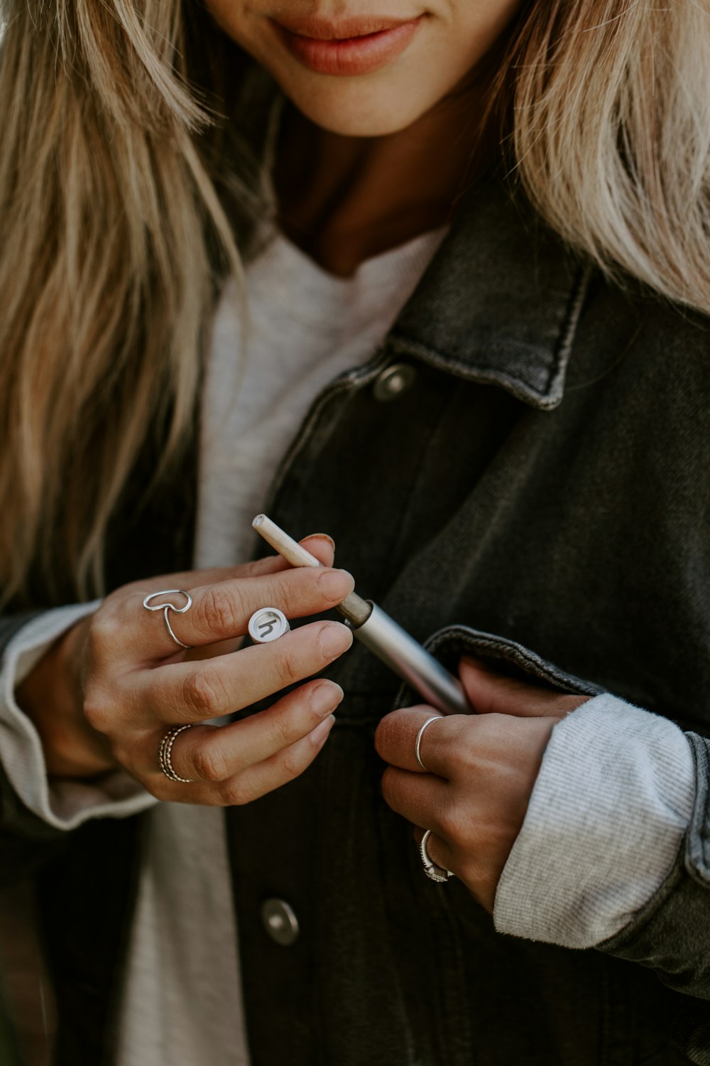 a woman is holding a cigarette and looking at her phone