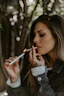 a woman smoking a cigarette next to a tree