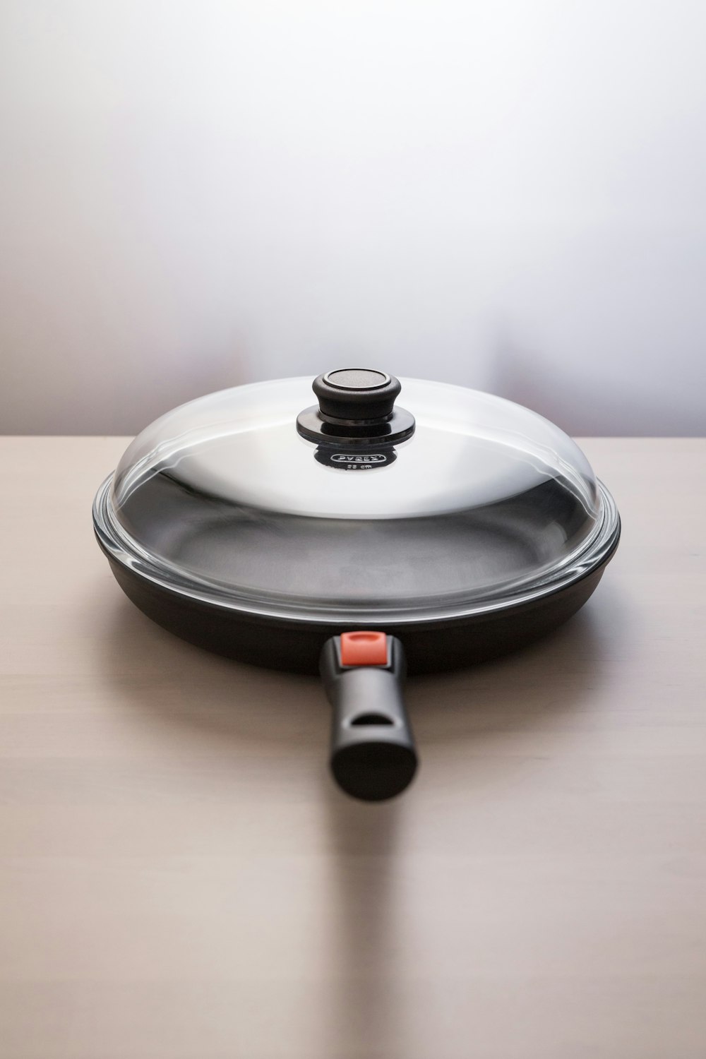 a silver pan with a black lid on a wooden table