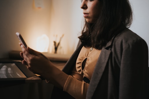 Elegant woman confidently using her smartphone in a stylish, feminine workspace.