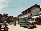 A panoramic view of a busy Indian road with travelers and colorful vehicles under a bright sky.
