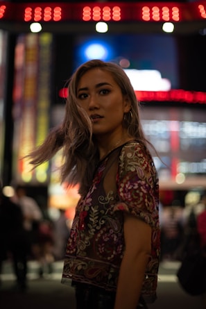 A young woman wearing a colorful Korean-style casual dress standing in a vibrant urban setting.