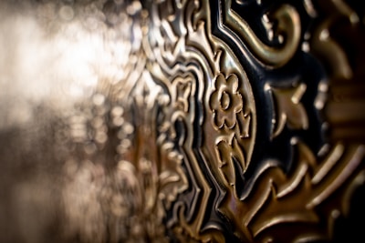 Intricate metalwork featuring ornate, embossed floral and geometric patterns with a soft focus on one side, giving a sense of depth and texture.
