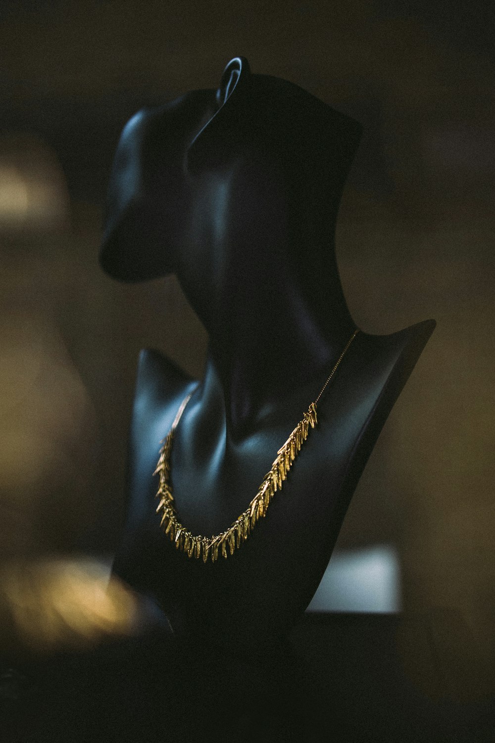 a black mannequin with a gold necklace on it