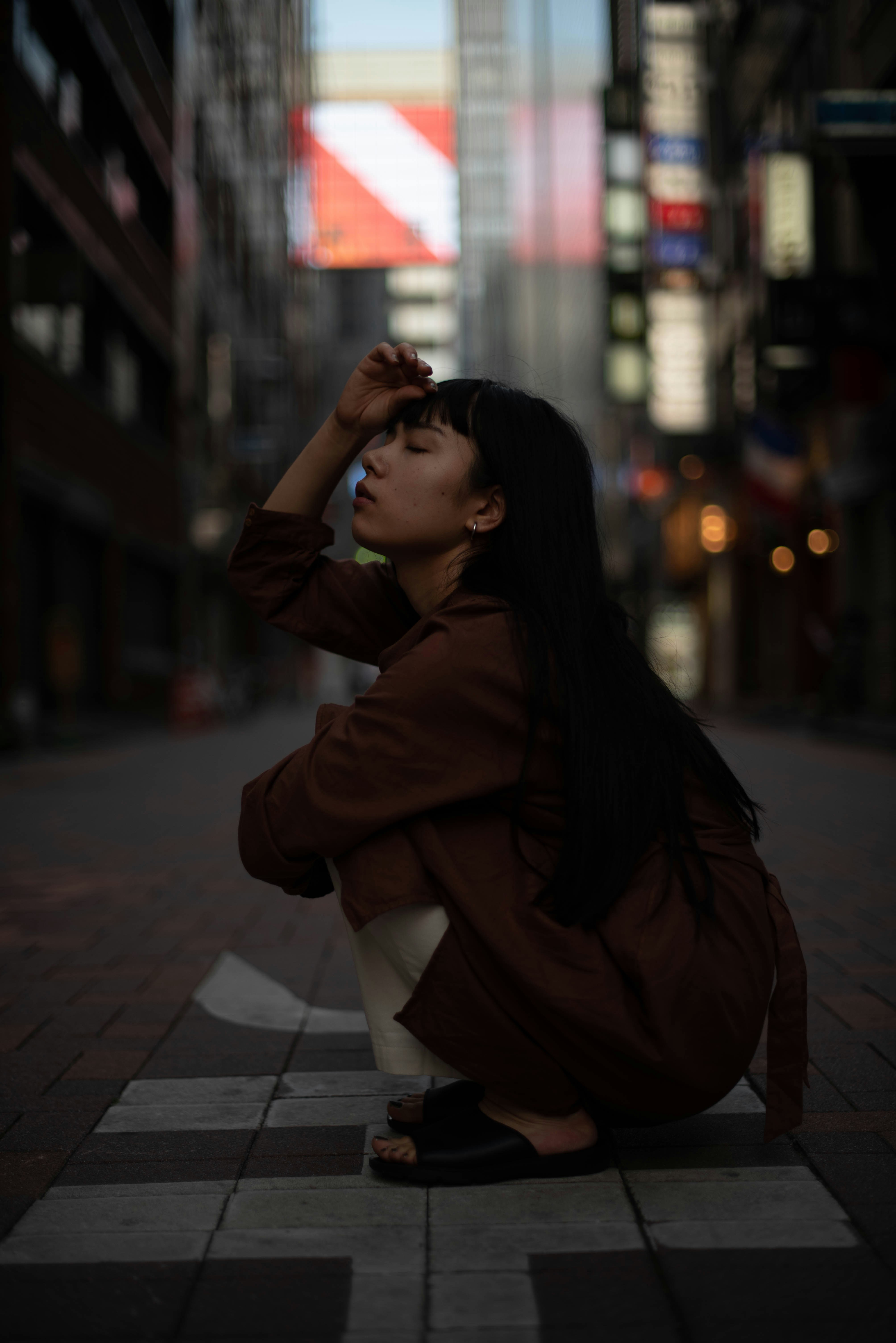a woman sitting on the ground in the middle of a city