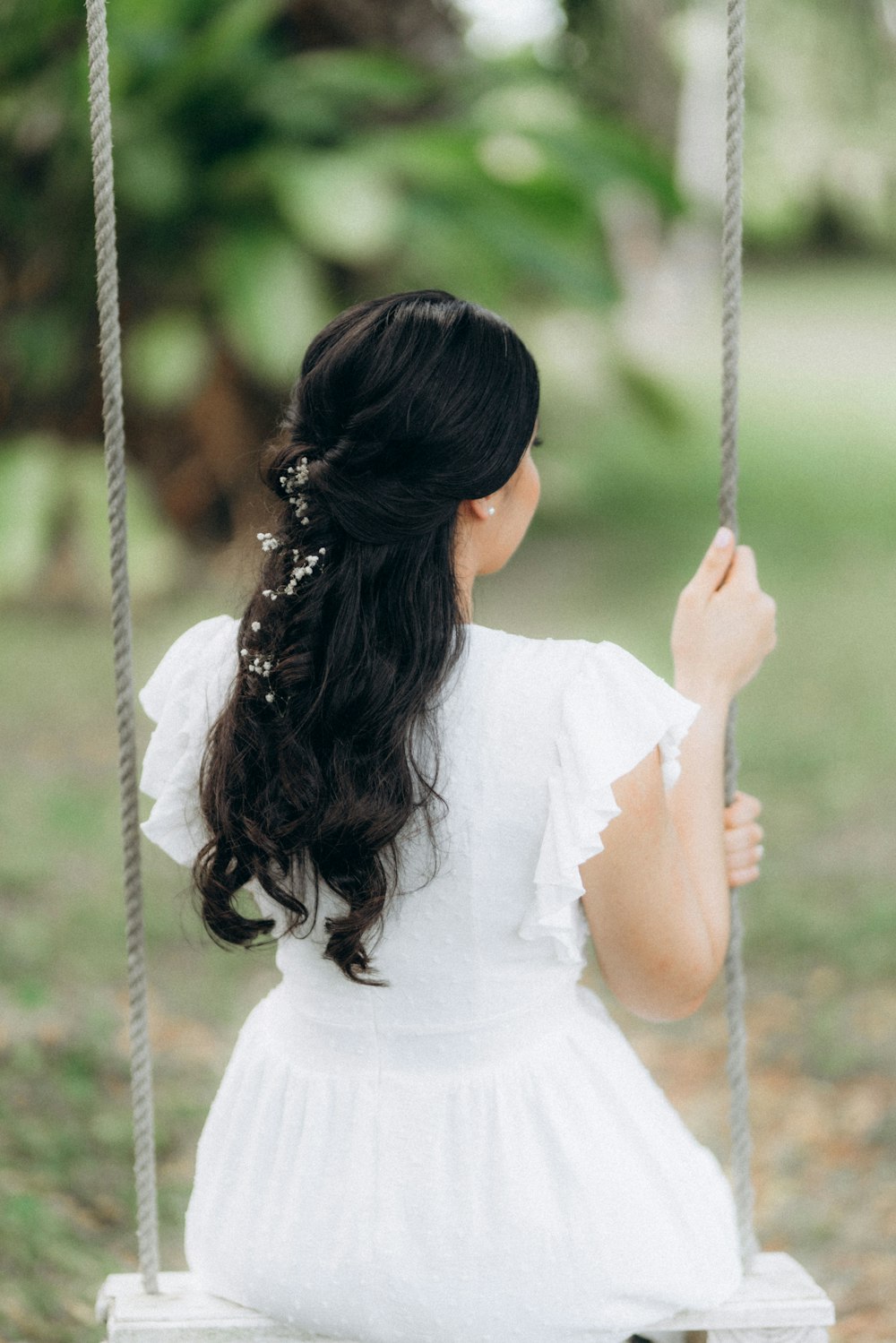 a woman in a white dress sitting on a swing
