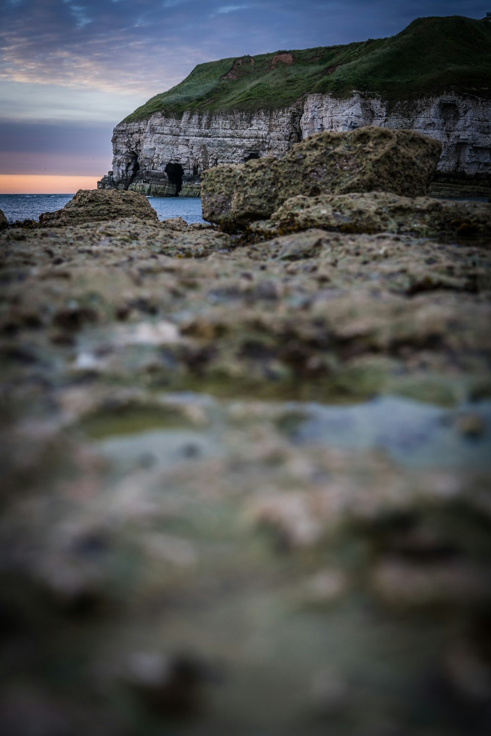 a rocky beach with a cliff in the background