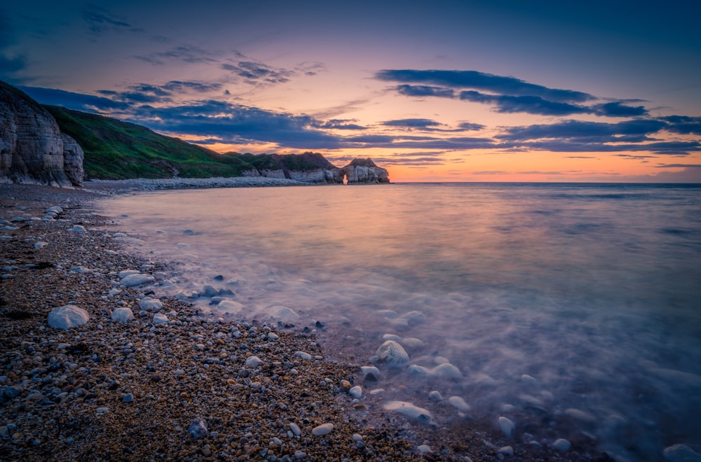 a house on the shore of a beach at sunset