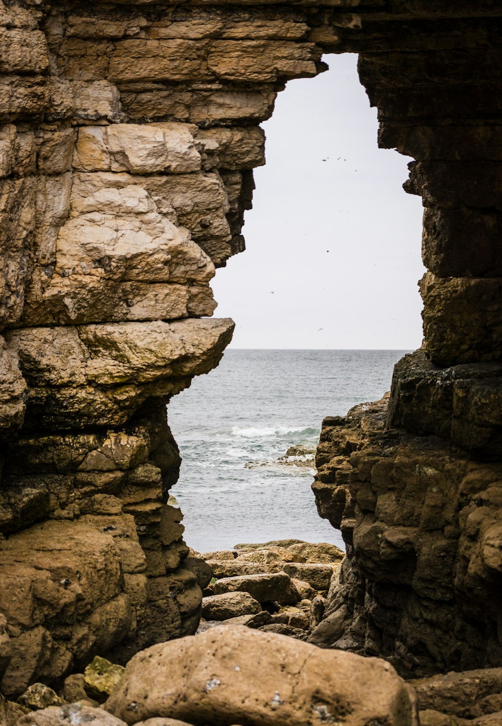 a view of the ocean through a window in a rock wall