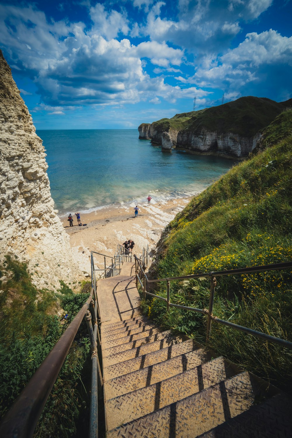 stairs lead down to a sandy beach with people on it
