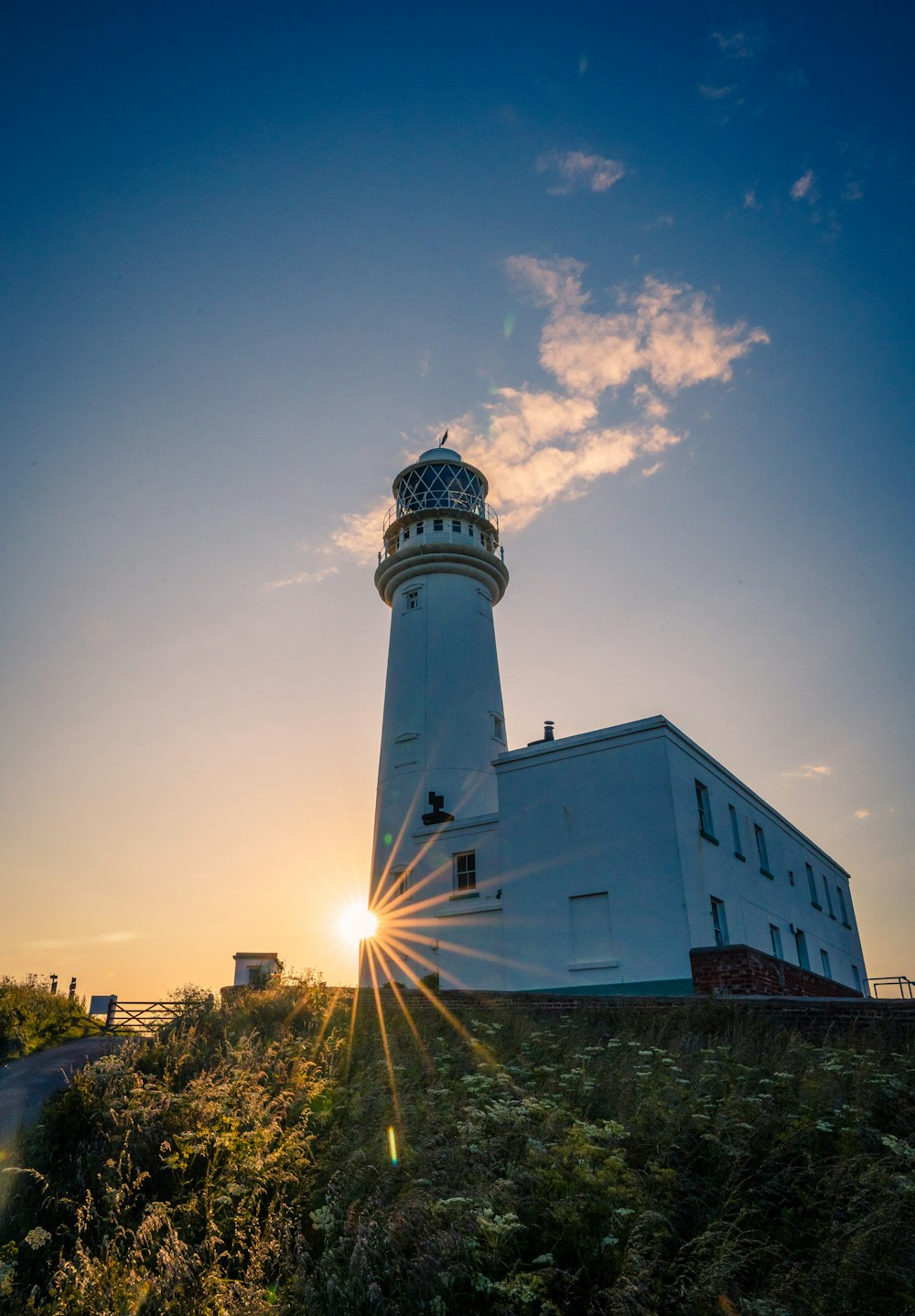 the sun is setting behind a lighthouse on a hill