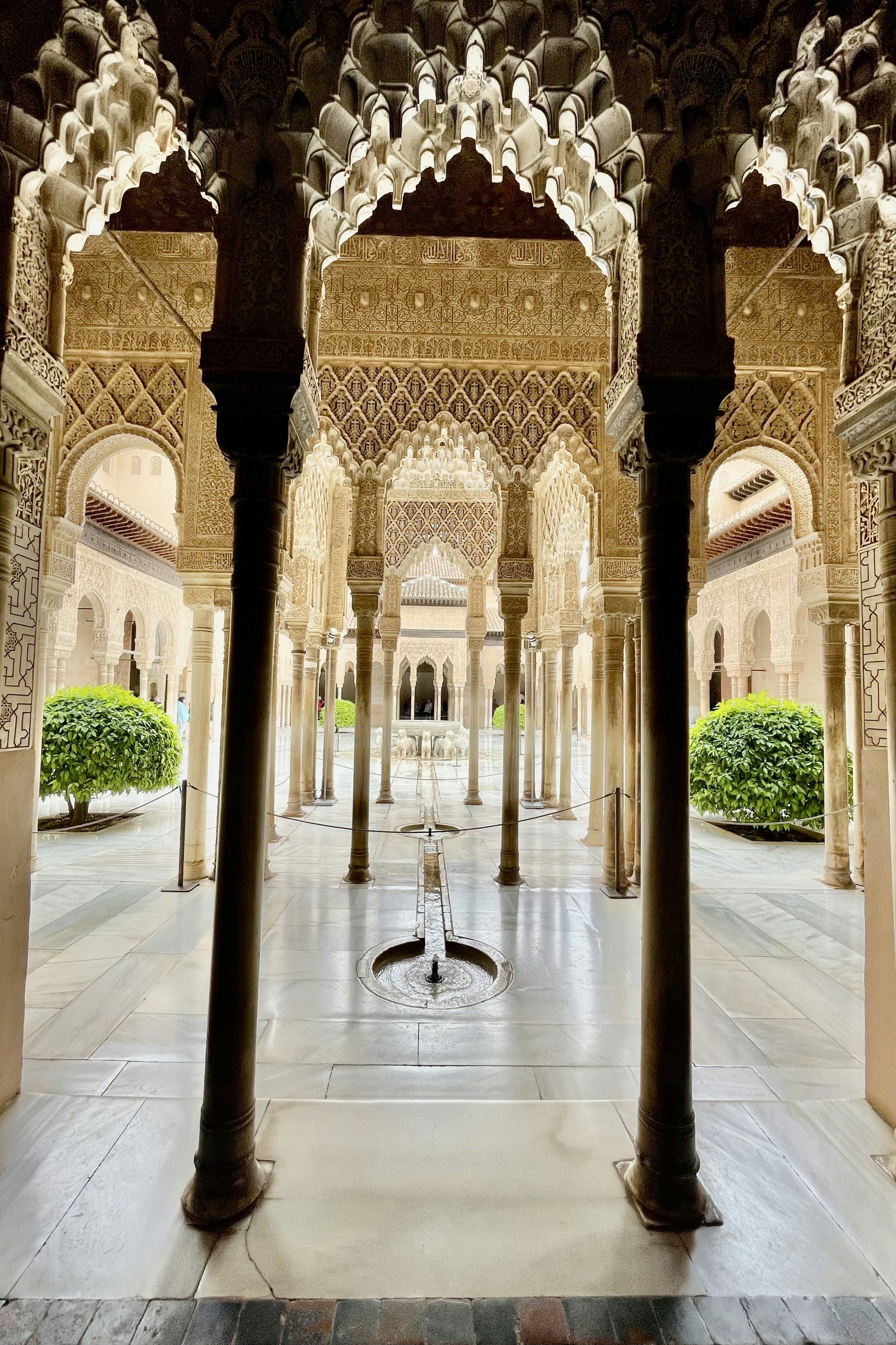 Palace courtyard with Mughal-style arched corridors, geometric garden patterns, central fountain, warm afternoon light