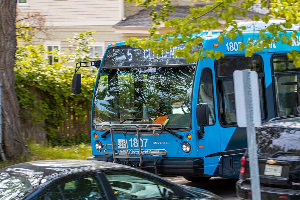 a blue bus driving down a street next to a car