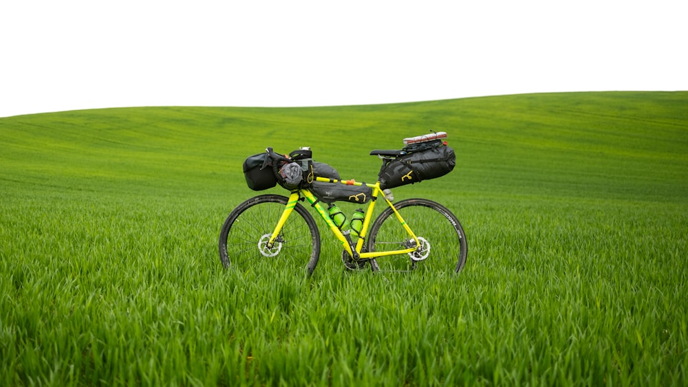 a bike with a backpack on the back parked in the middle of a field
