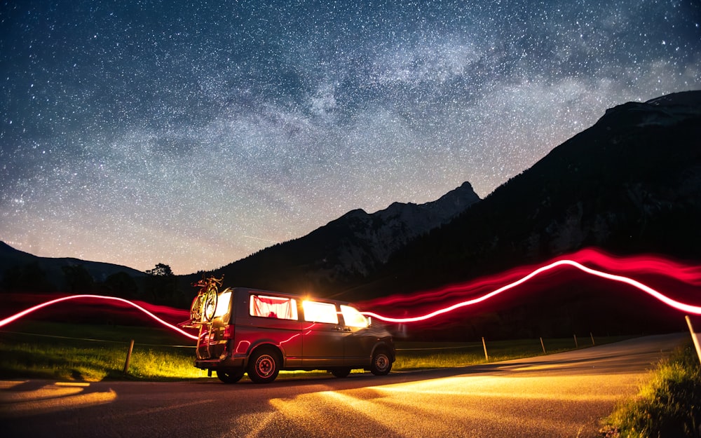 a van driving down a road under a night sky filled with stars