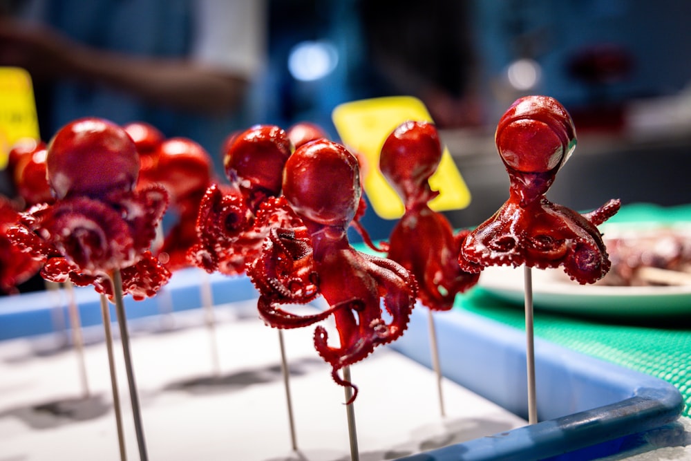 a row of red octopus lollipops sitting on top of a blue tray