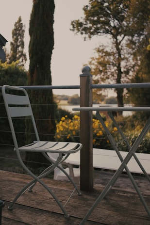 A cozy 5-piece outdoor dining set arranged on a sunlit wooden deck surrounded by lush greenery.