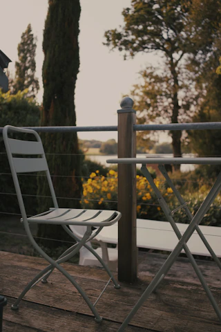 An inviting outdoor aluminum recliner placed on a wooden deck surrounded by greenery.