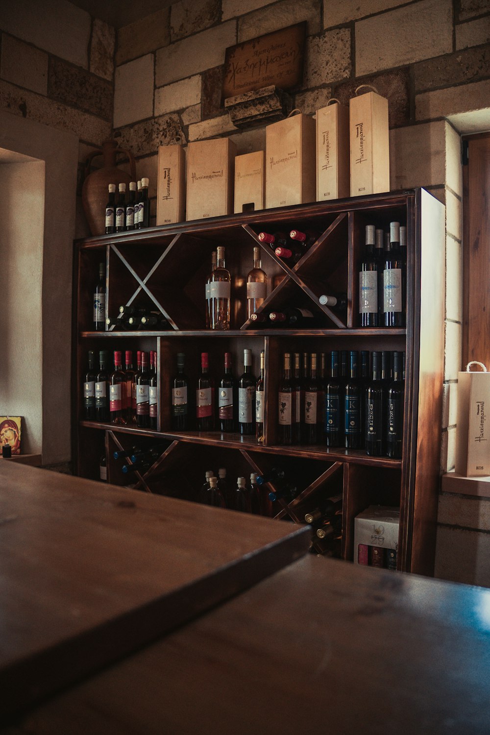 a wooden table sitting in front of a shelf filled with bottles