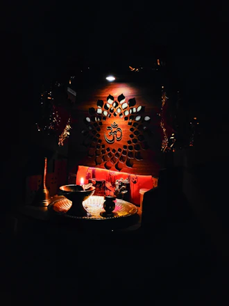 A serene display of brass pooja items arranged on a traditional wooden altar bathed in soft, warm light.
