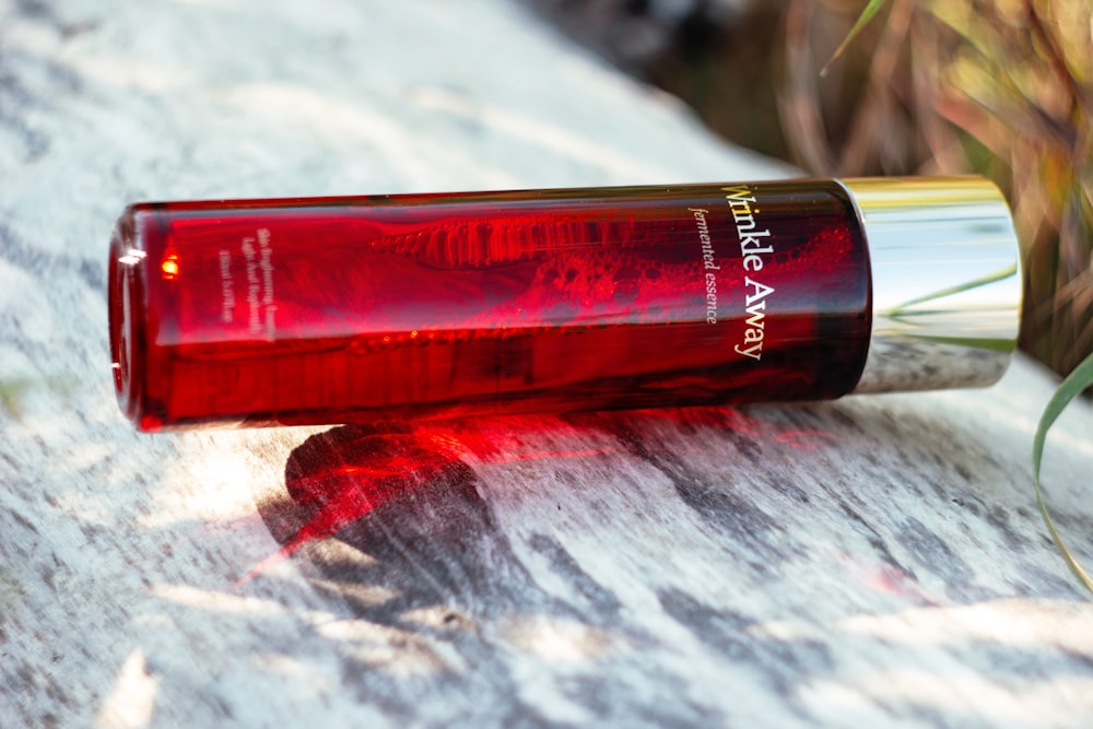 a close up of a red bottle on a rock