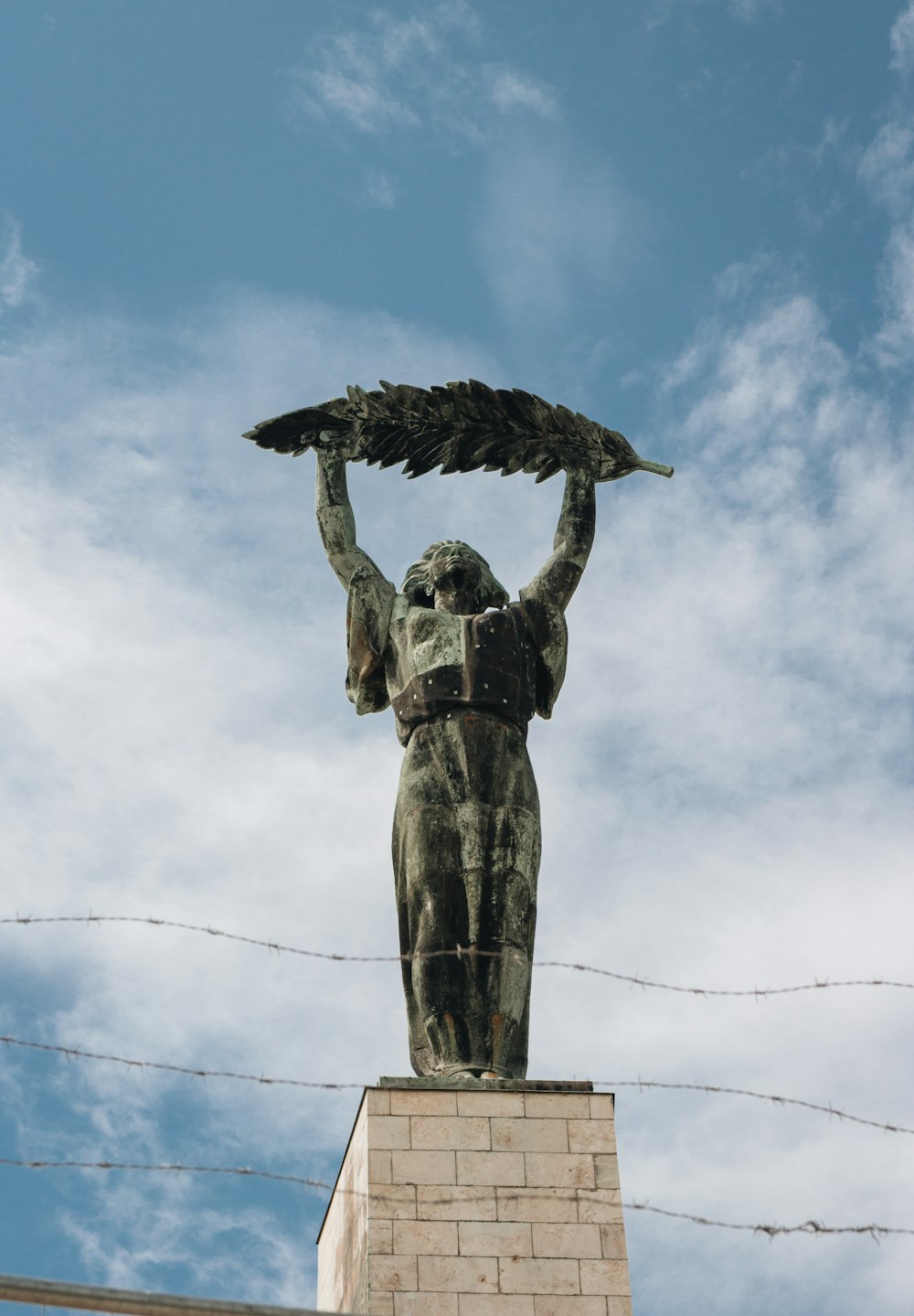 a statue of a woman holding a bird on top of a building