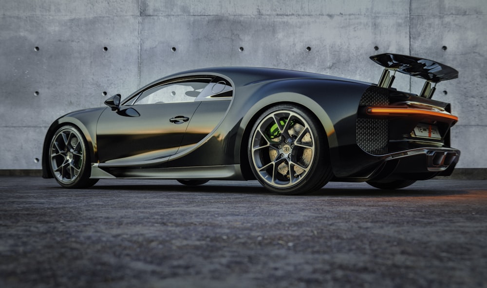 a black sports car parked in front of a concrete wall