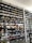 A shoe store wall filled with multiple rows of sneakers, displaying a variety of brands, styles, and colors. The sneakers are arranged neatly on black shelves against a white wall. There are hints of other merchandise and clothing visible in the background.