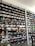 A shoe store wall filled with multiple rows of sneakers, displaying a variety of brands, styles, and colors. The sneakers are arranged neatly on black shelves against a white wall. There are hints of other merchandise and clothing visible in the background.