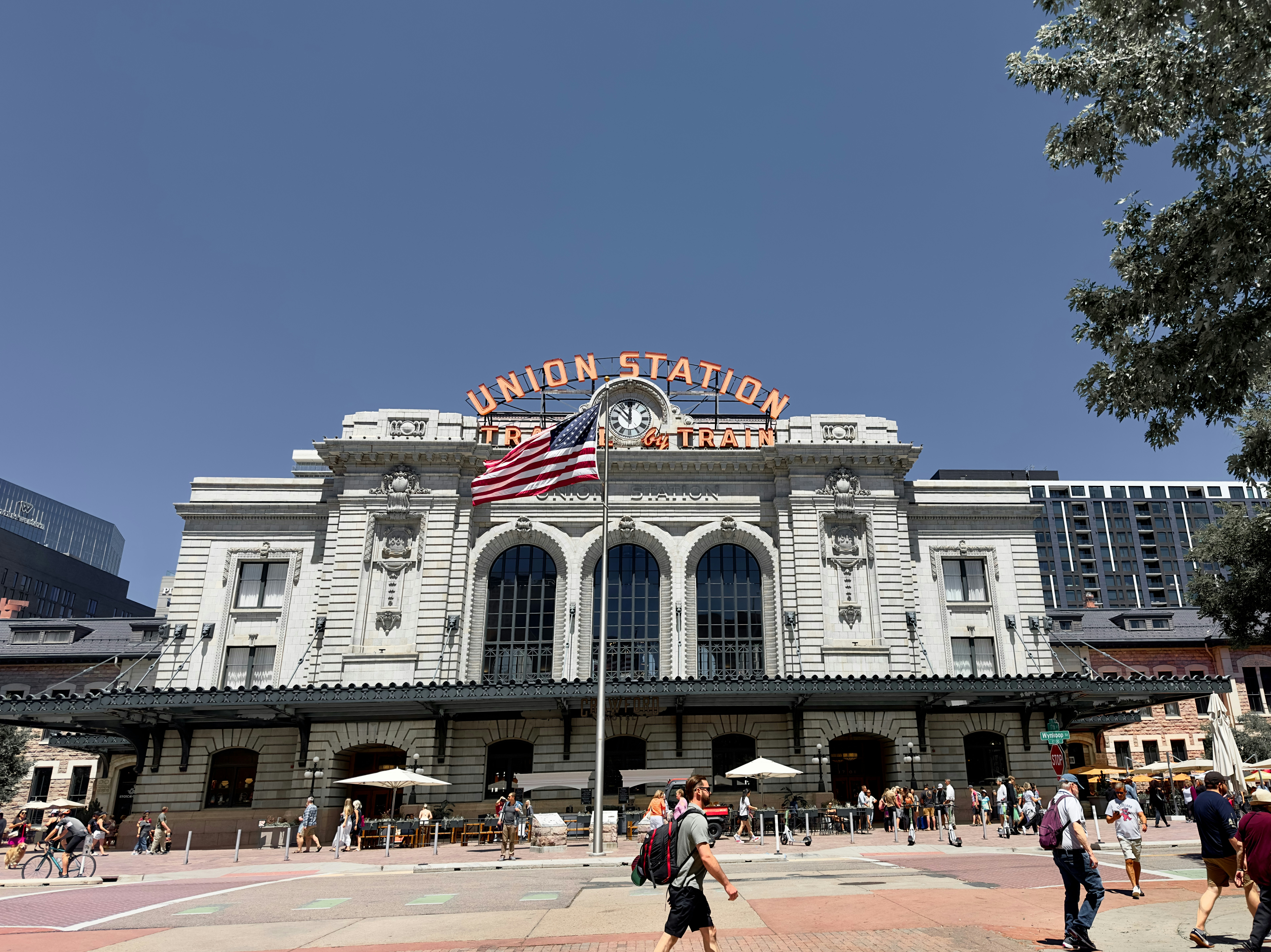 a group of people walking in front of a train station
