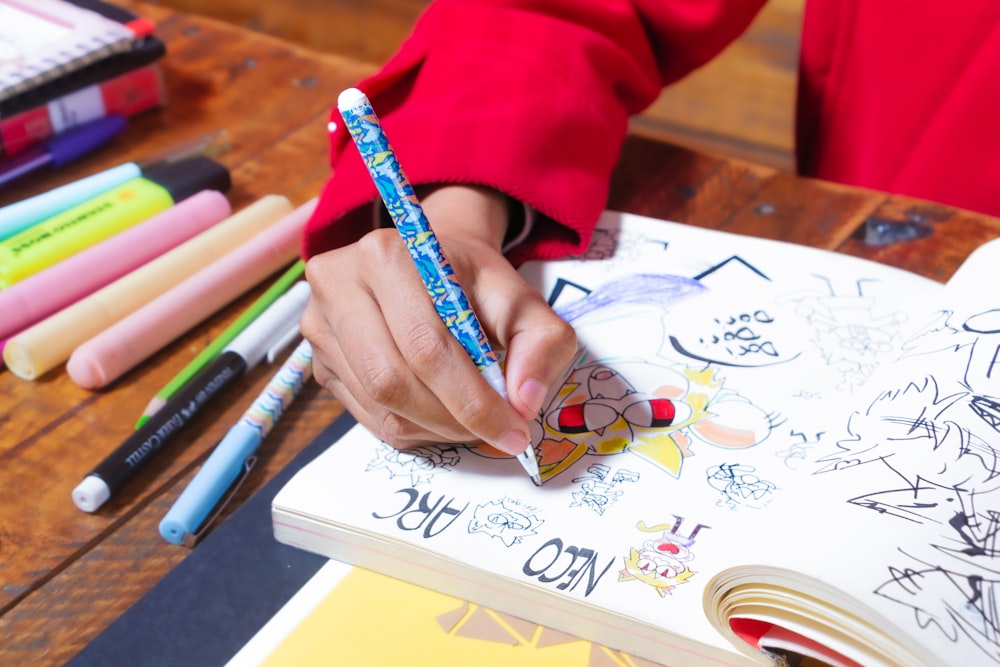 a person is writing on a book with markers