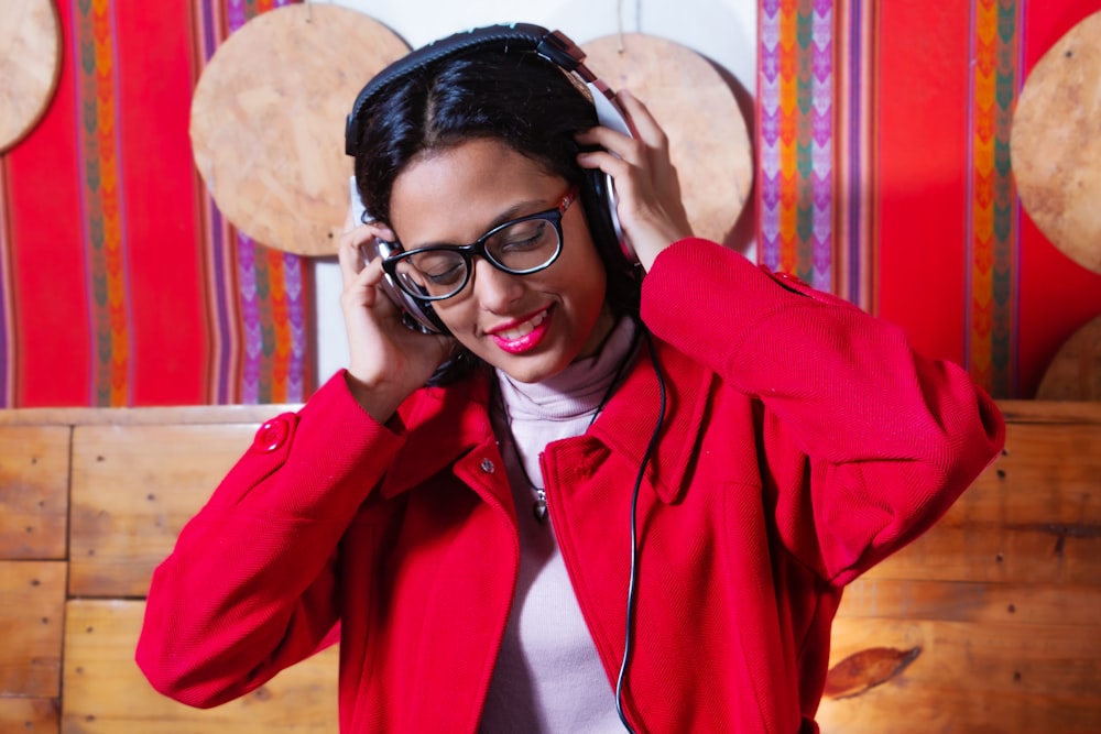 a woman in a red jacket listening to headphones