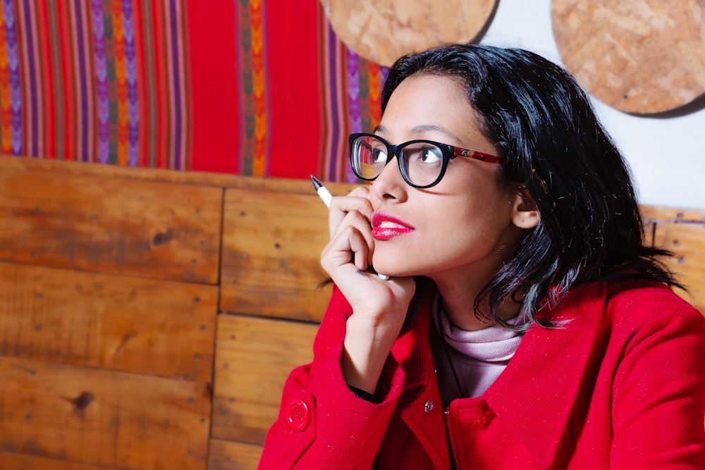 a woman in a red coat smoking a cigarette