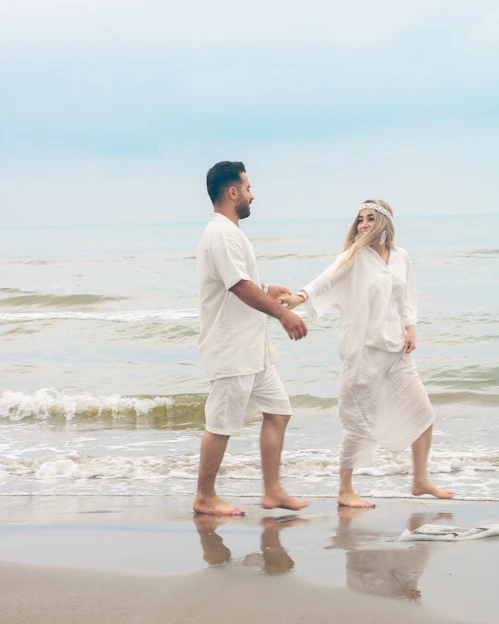 A joyful couple walking barefoot along a turquoise Caribbean beach at sunset, surrounded by tropical flowers and soft waves.