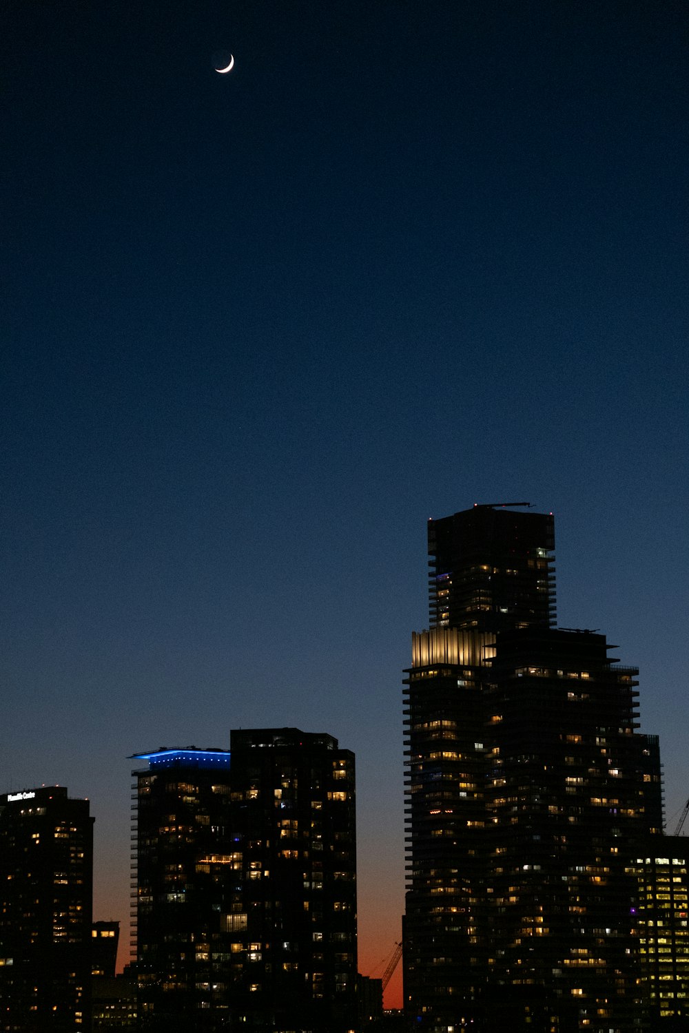 a view of a city at night with the moon in the sky