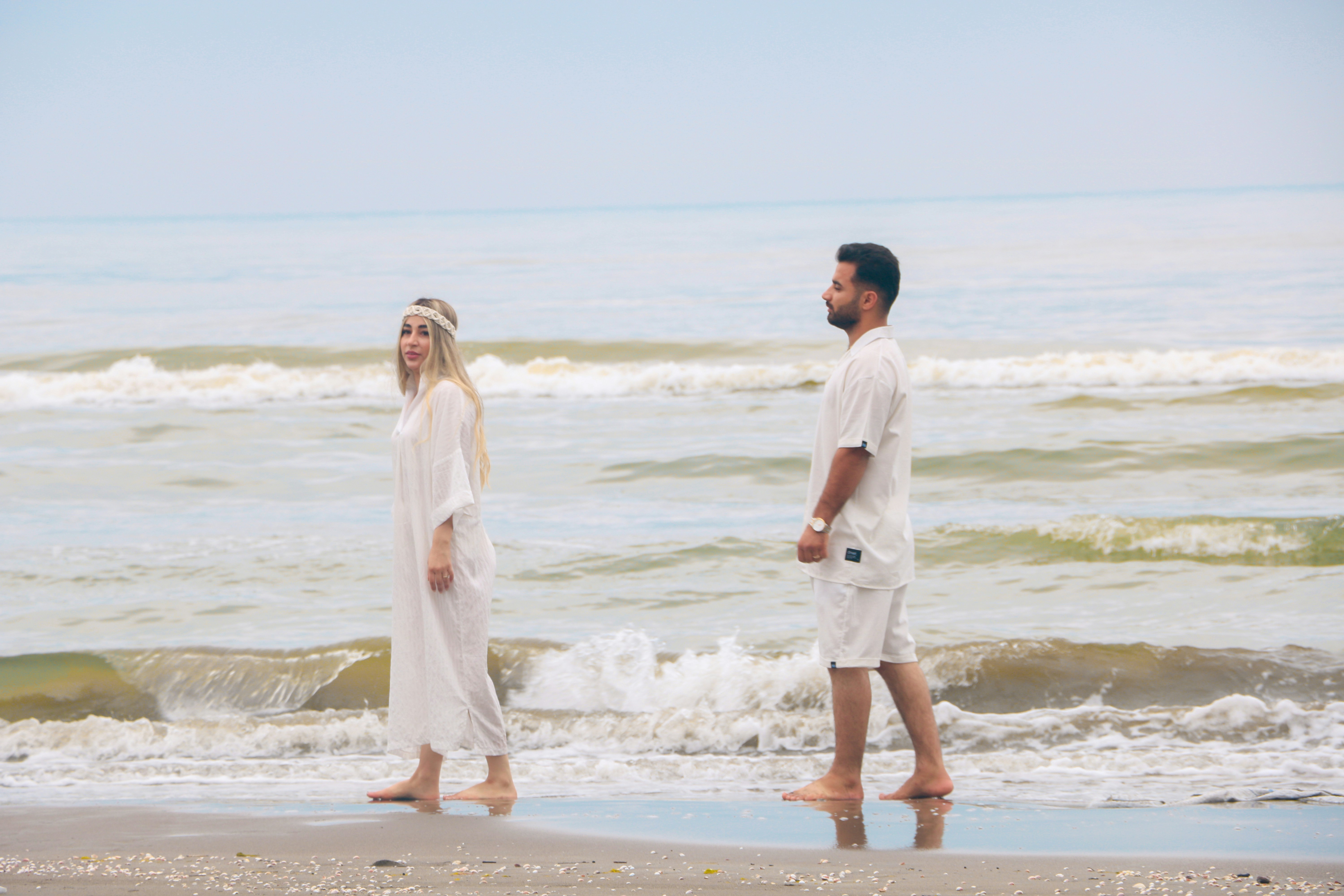 Un uomo e una donna camminano scalzi lungo la riva dell'oceano