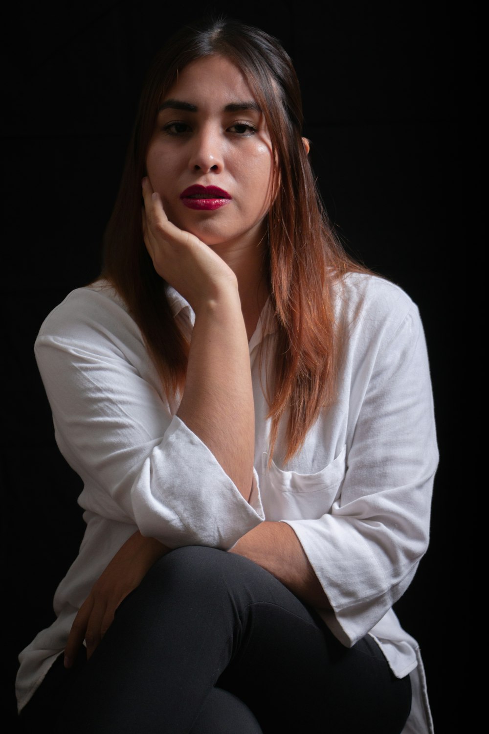 a woman sitting down with her hand on her chin