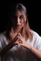 a woman in a white shirt holding her hands together