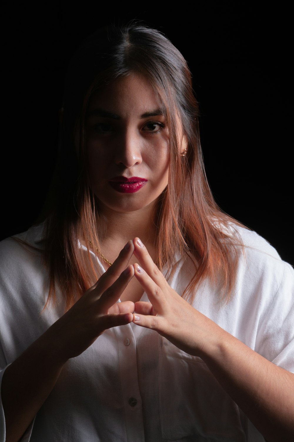 a woman in a white shirt holding her hands together