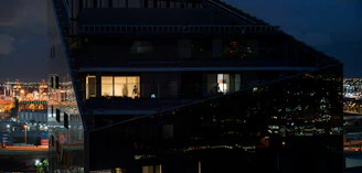 Drone shot of a luxury glass facade building reflecting city lights at night.