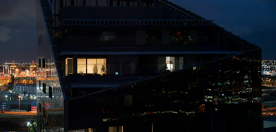 Drone shot of a luxury glass facade building reflecting city lights at night.
