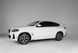 A sleek white SUV with a modern design, featuring dark tinted windows and stylish black alloy wheels. The vehicle is positioned against a neutral gray background, highlighting its streamlined silhouette and sporty appearance.