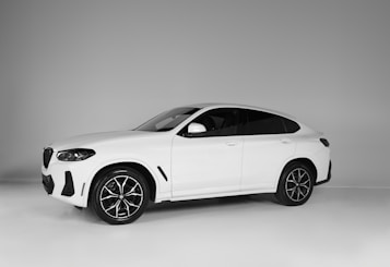 A sleek white SUV with a modern design, featuring dark tinted windows and stylish black alloy wheels. The vehicle is positioned against a neutral gray background, highlighting its streamlined silhouette and sporty appearance.