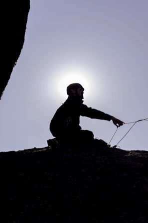 a man sitting on top of a rock next to a kite