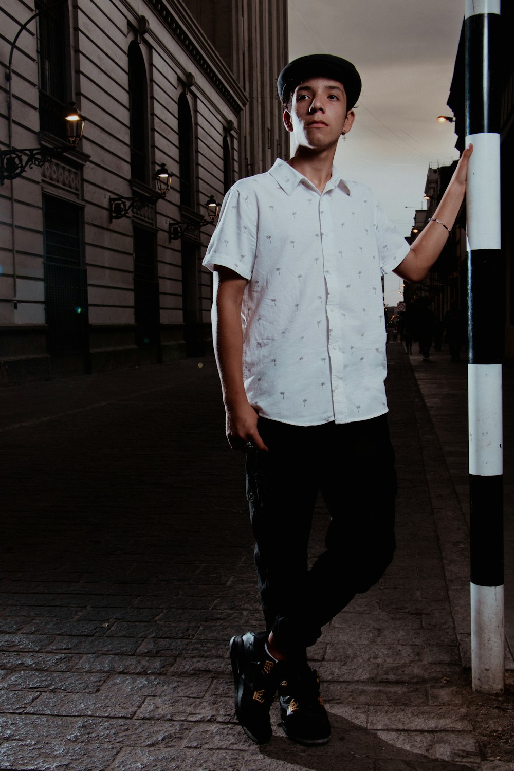 a man standing next to a pole on a sidewalk