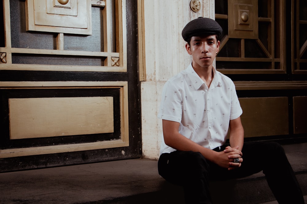 a man sitting on the ground in front of a building